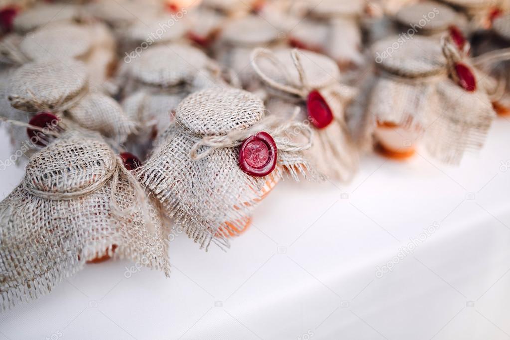 Honey and jam in jars decorated with burlap and stamped on the table with a white tablecloth