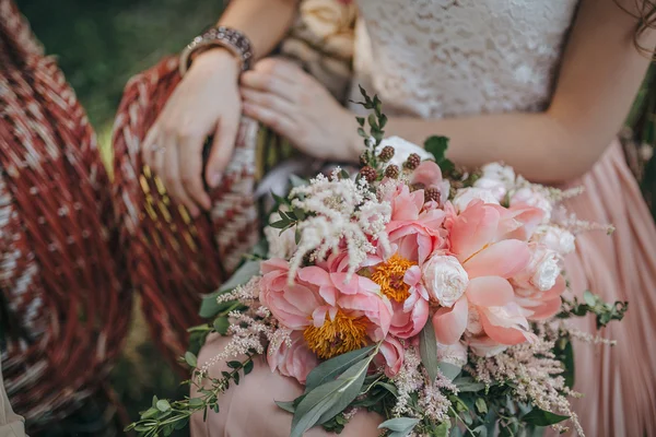 Gadis duduk di kursi taman wicker dan memegang karangan bunga merah muda dan putih peoni dan hijau — Stok Foto