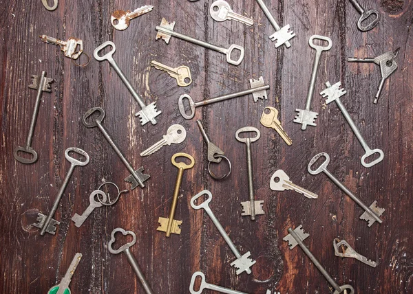 Some door keys aligned on old wooden surface, safety and security concept background