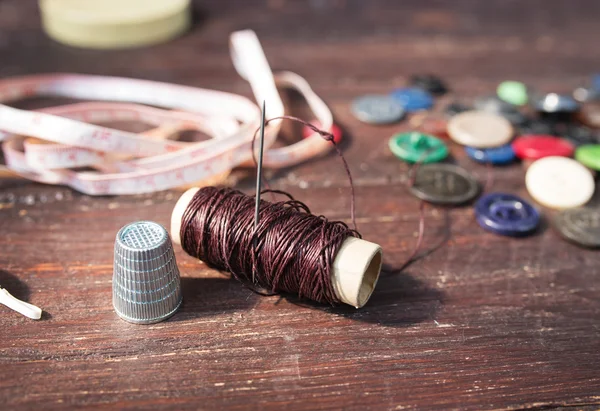 Spools of threads and buttons on old wooden table — Stock Image Spools of threads and buttons on old wooden table Stock Picture