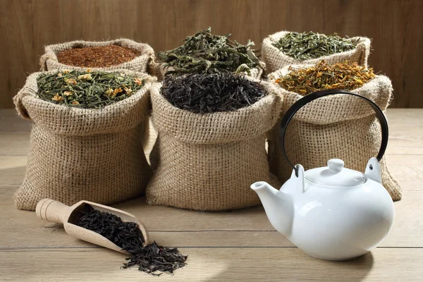 Assortment of fragrant dried teas and green tea on dark wooden table, horizontal — Stock Photo, Image