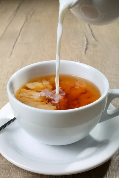 Taza de té con leche vertiendo en — Foto de Stock