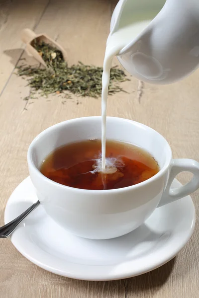 Šálek čaje s mlékem nalil do — Stock fotografie