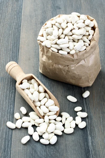 White beans in spoon and paper bag — Stock Photo, Image