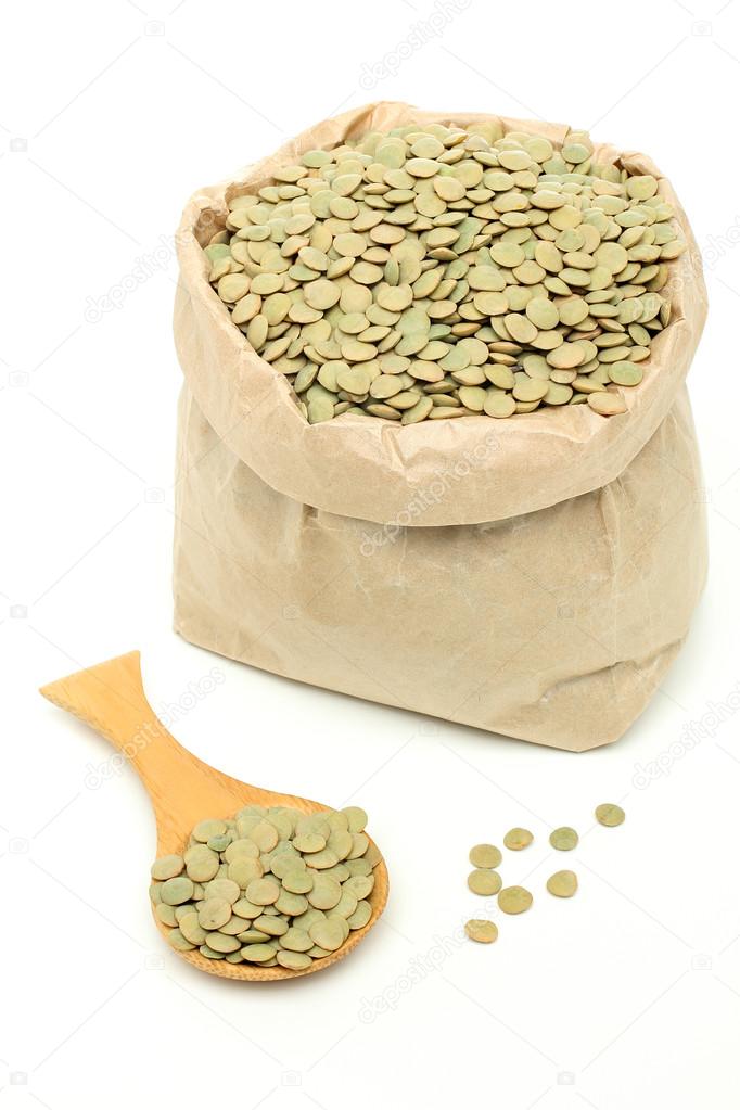 Green lentils in spoon and paper bag
