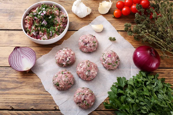 Ruwe gehaktballen met ingrediënten op houten achtergrond — Stockfoto