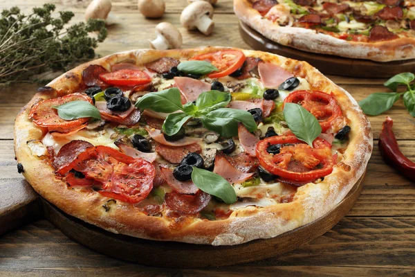 Pizza with ham tomato slice and pepperoni on rustic wooden table — Stock Photo, Image