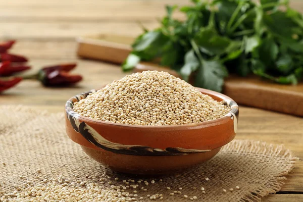 Raw Quinoa seeds in ceramic bowl on rustic kitchen table background — Stock Photo, Image