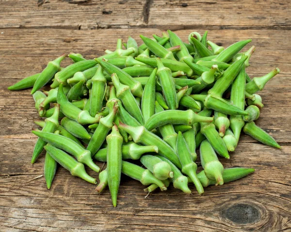 Okra på ett träbord — Stockfoto