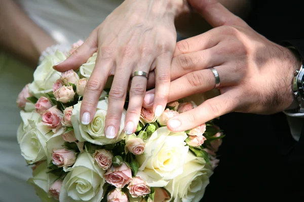 Le mani di coppia nuziale su mazzo rosa — Foto Stock