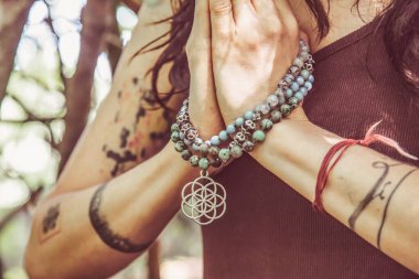 Ormanda Mala kolyesiyle namaste mudra yogası yapan kadın eller.