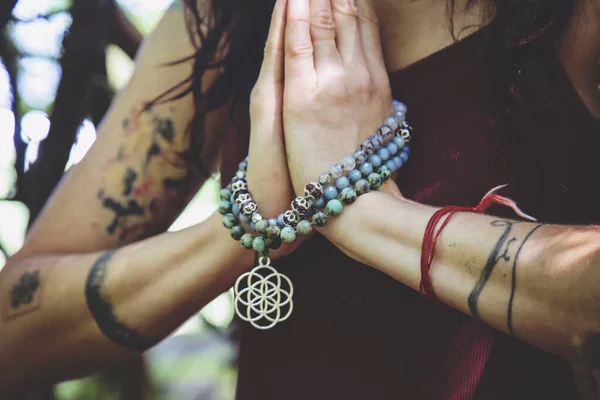Ormanda Mala kolyesiyle namaste mudra yogası yapan kadın eller.