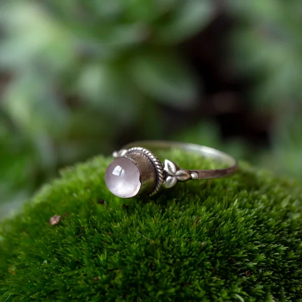 Sterling silver ring with rose quartz gemstone on green moss background