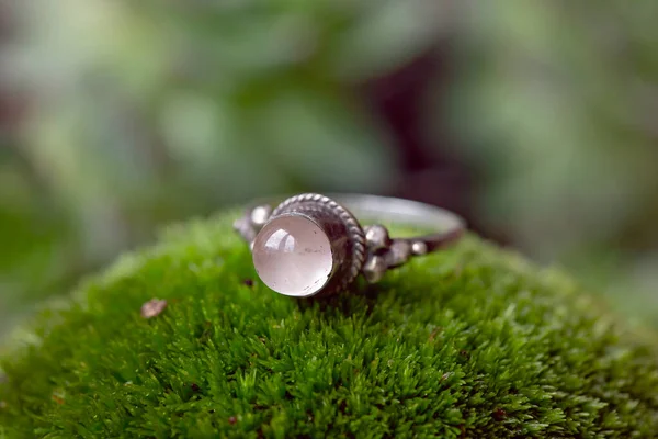 Sterling silver ring with rose quartz gemstone on green moss background