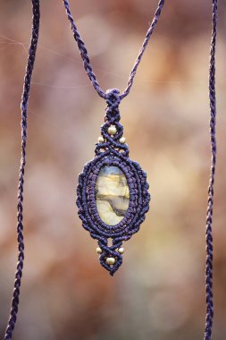 Bulanık orman arka planında mineral labradorit değerli taş süsleme kolyesi