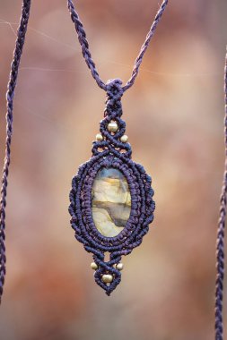 Bulanık orman arka planında mineral labradorit değerli taş süsleme kolyesi