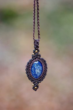 Bulanık orman arka planında mineral lapis lazuli değerli taş süsleme kolyesi