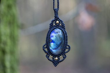 Bulanık orman arka planında mineral labradorit değerli taş süsleme kolyesi