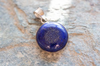 Kayalık arka planda mineral lapis lazuli değerli taşlı saf gümüş kolye.