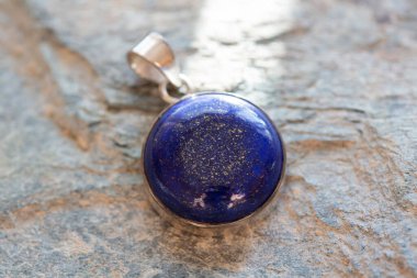 Kayalık arka planda mineral lapis lazuli değerli taşlı saf gümüş kolye.