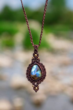 Boho tarzında güzel bir kolye, labradorit mineral taşıyla doğal bulanık arkaplan.