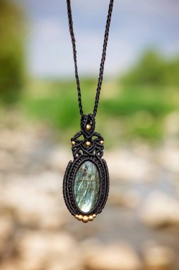 Boho tarzında güzel bir kolye, labradorit mineral taşıyla doğal bulanık arkaplan.