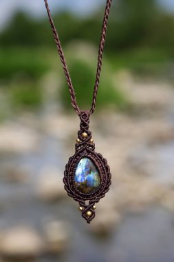 Boho tarzında güzel bir kolye, labradorit mineral taşıyla doğal bulanık arkaplan.