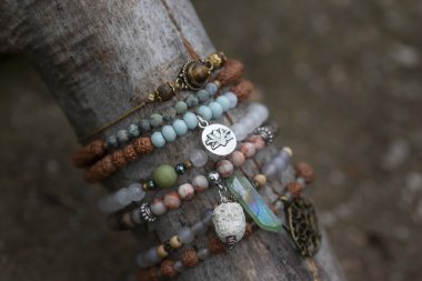 Tahta çubuk üzerinde mineral taş bilezik koleksiyonu.