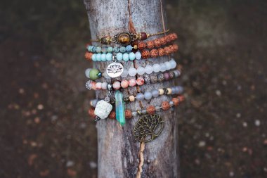 Tahta çubuk üzerinde mineral taş bilezik koleksiyonu.