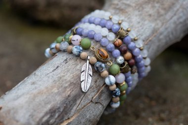 Tahta çubuk üzerinde mineral taş bilezik koleksiyonu.