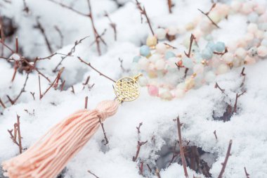 Beyaz kardaki yantra yüzlü morganit mala kolyesinin pirinç metal ruhani sembolü.