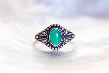 Beyaz kabuklu yeşil taşlı antik gümüş bir yüzük.