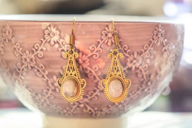 Pirinç metal mineral küpeler bir kasede asılı.