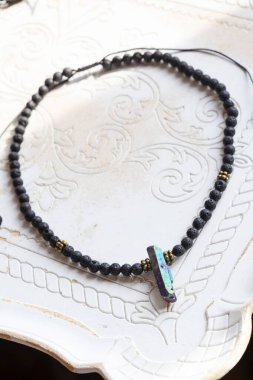 Beyaz dekoratif arka planda titanyum lav taşı kolyeli kristal kuvars.