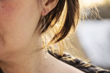 Uzun labradorit mineral taş küpe takan bir kadın kulak.