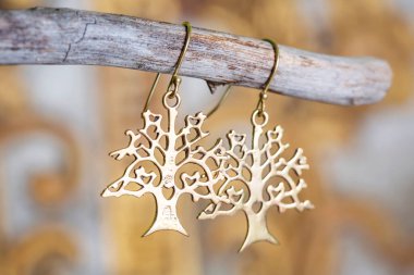 Tarafsız arkaplanda asılı süs şeklinde pirinç metal küpeler.