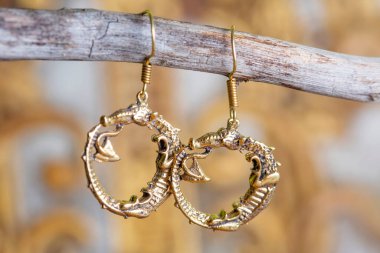 Tarafsız arkaplanda asılı süs şeklinde pirinç metal küpeler.