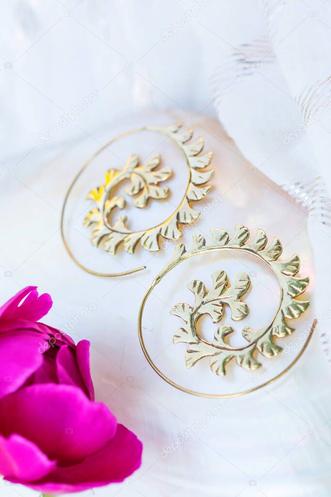 Beautiful brass metal earrings on neutral natural background