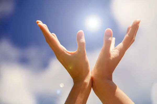 Hands holding light on the blue sky — Stock Photo, Image