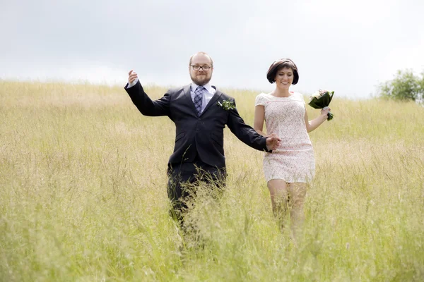 Young wedding couple running in the field — Stock Photo, Image