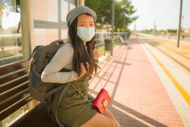 Genç, güzel ve mutlu bir Asyalı turist. Yeni normal, çekici bir Koreli kız sırt çantasıyla istasyonda trenini beklerken turizm yapıyor. 