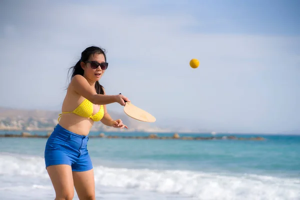 休日のライフスタイルの肖像画若い幸せとかわいいアジアの日本の女性は海で夏休みを楽しんでビーチでラケットを保持パドルボールを果たしています — ストック写真