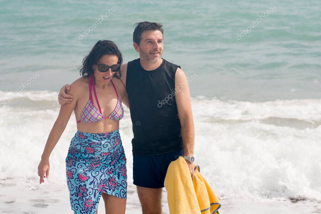 attractive and happy couple enjoying beautiful holidays walking cheerful and relaxed on the beach along the sea smiling playful in love and romantic travel concept