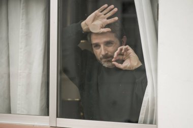 Çekici üzgün ve depresif orta yaşlı bir adamın dramatik portresi. Ev penceresinden bakan endişeli ve umutsuz acı çeken depresyon sorunu düşünceli. 