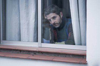 Çekici üzgün ve depresif orta yaşlı bir adamın dramatik portresi. Ev penceresinden bakan endişeli ve umutsuz acı çeken depresyon sorunu düşünceli. 