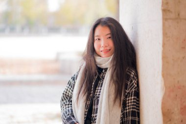 Genç ve güzel Asyalı Japon turist kadının hayat tarzı portresi mutlu bir şekilde gülümsüyor. Güneşli bir kış günü, tatil ve turizm için tarihi bir bölgede geziniyor.