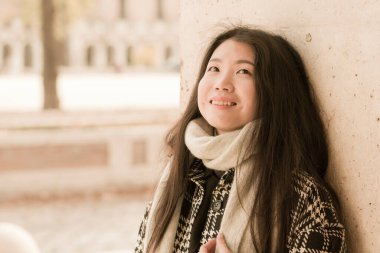 Genç ve güzel Asyalı Japon turist kadının hayat tarzı portresi mutlu bir şekilde gülümsüyor. Güneşli bir kış günü, tatil ve turizm için tarihi bir bölgede geziniyor.