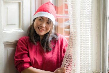 Noel Baba şapkalı, kırmızı formalı, güzel ve mutlu Asyalı bir Japon kadının Noel 'in tadını çıkartan mutlu bir şekilde portresi. 