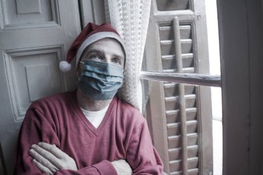 Noel Baba şapkalı ve maskeli depresif ve yorgun bir adam, yalnız başına Coronavirus yasağı yüzünden acı çekiyor.