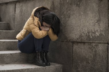 Çekici, üzgün ve depresif Koreli bir kadının dramatik yaşam tarzı portresi. Kışlık ceketli, sokak köşesindeki merdivenlerde oturmuş depresyon sorunu yaşıyor. Çaresiz hissediyor.